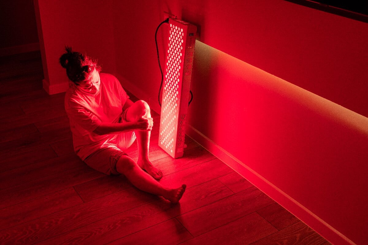 elderly-woman-sitting-near-red-light-therapy-device
