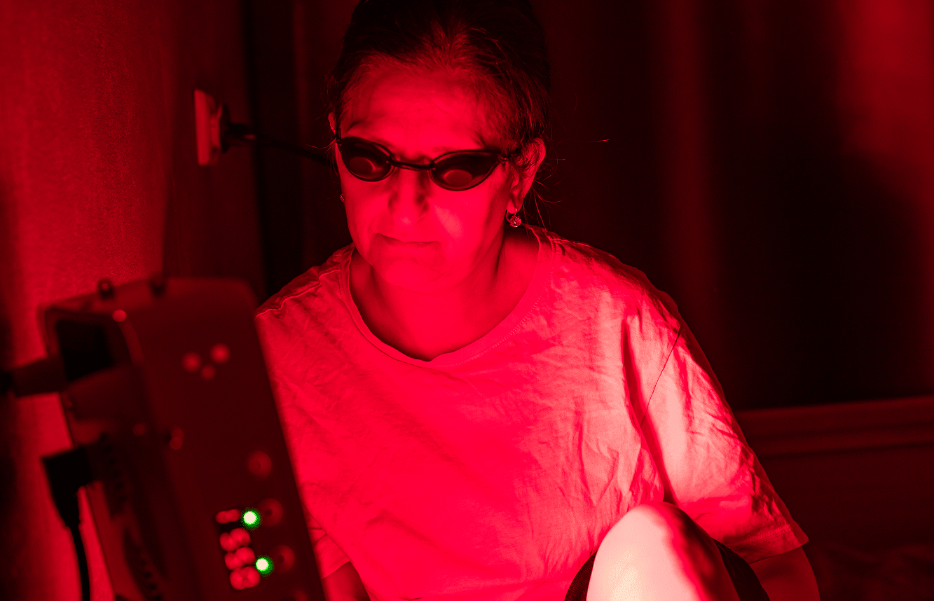 senior-woman-treating-sore-leg-with-the-red-light-therapy